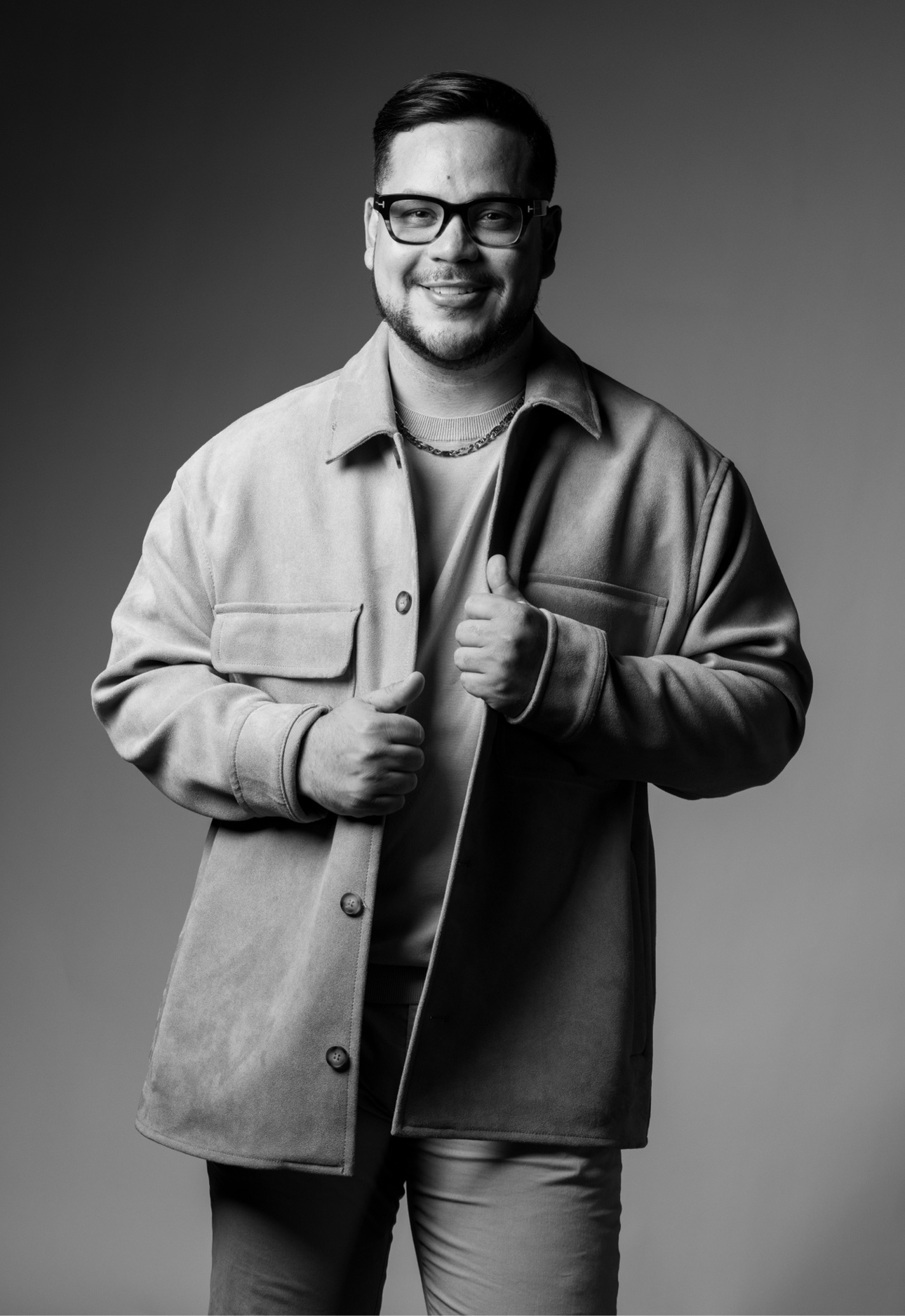 Black-and-white editorial portrait of a man wearing glasses