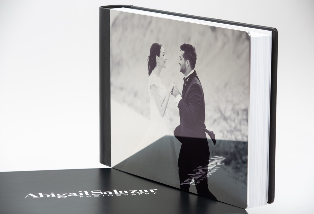 Luxury wedding album standing upright with a black-and-white couple portrait beneath an acrylic cover