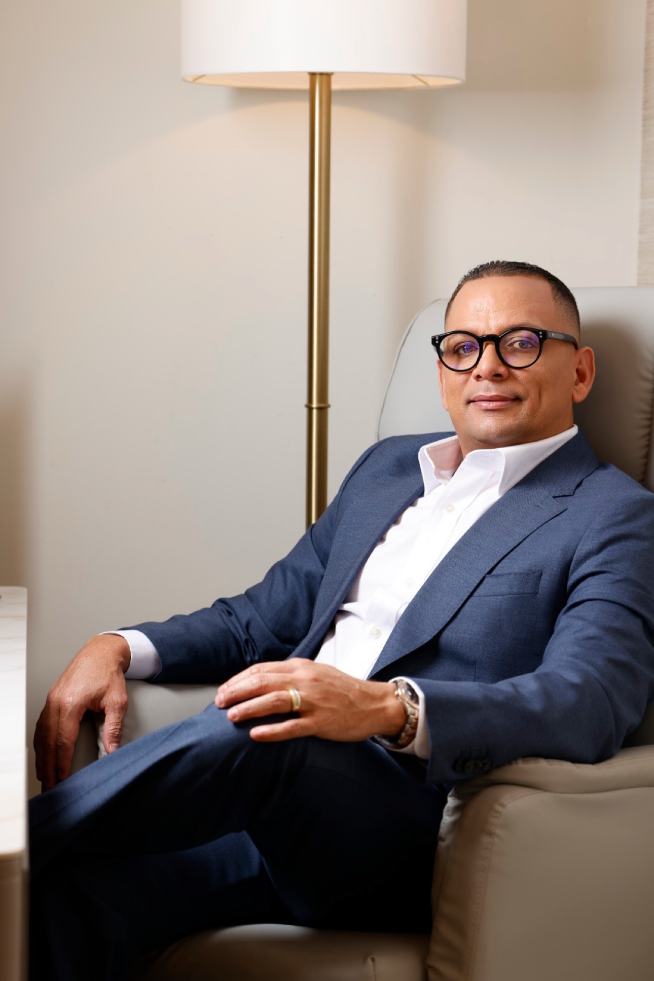 Executive in a blue suit and glasses seated in a refined office
